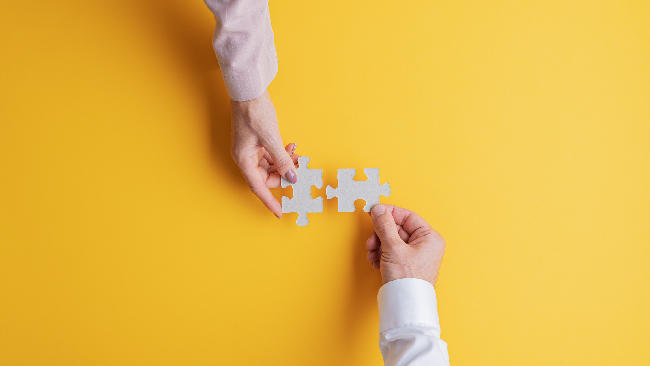 Male and Female Hands Joining Two Matching Puzzle Pieces Togethe